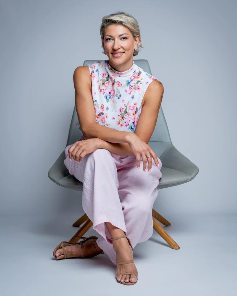 Retrato de Mariana Zhytariuk con blusa floral y pantalón rosa en el estudio.