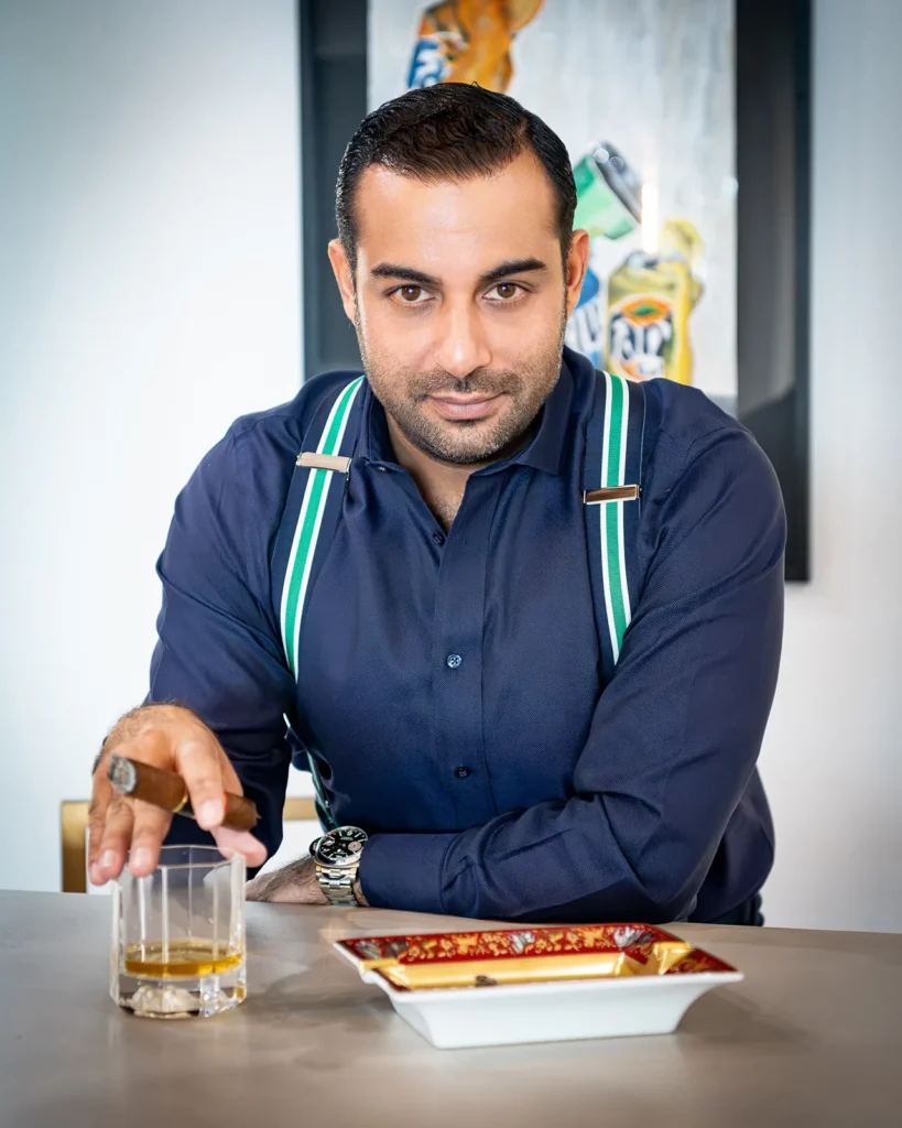Retrato editorial de Kabir Sukhwani con un puro y whisky