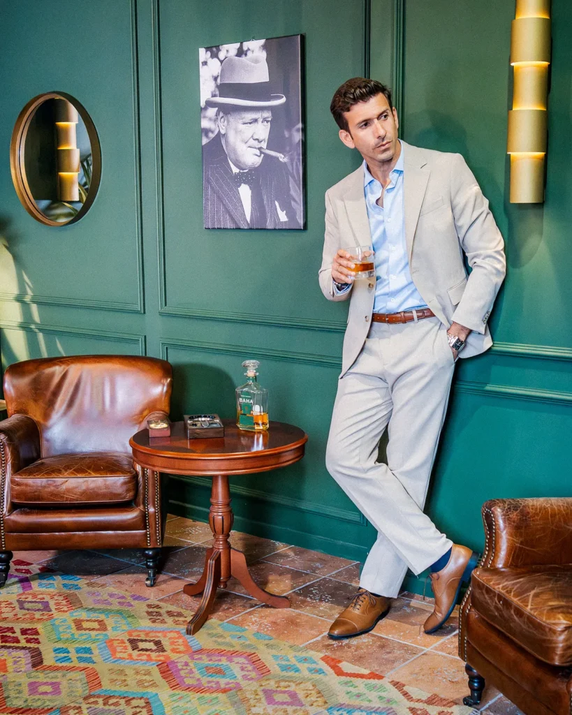 Retrato de Javier Nicolas con un vaso de whisky en un salón de estilo clásico.