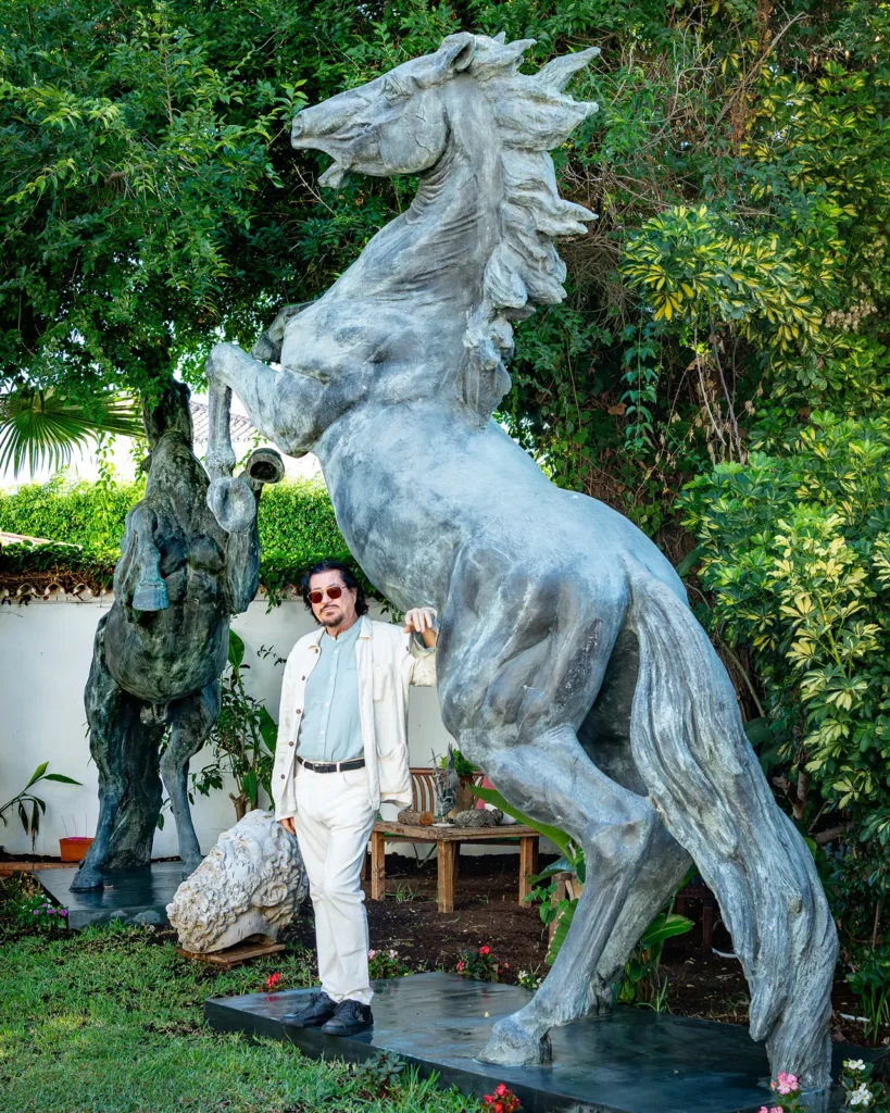 Retrato de Ginés Serrán Pagán junto a una escultura de caballo de bronce en el jardín de su casa en Marbella.